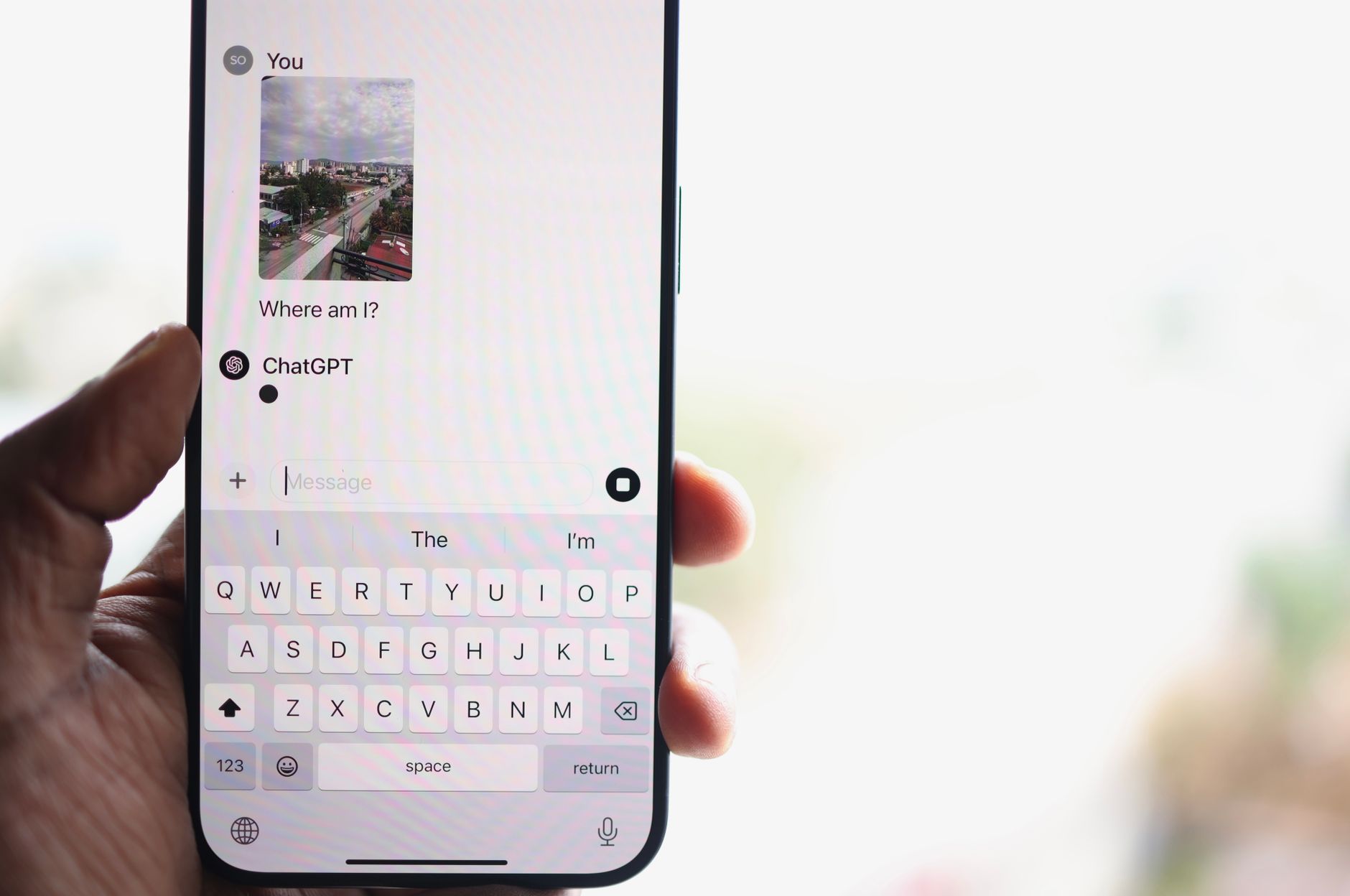 chatgpt on whatsapp now supports image inputs and voice messages - A person holds a smartphone displaying a chat with ChatGPT, inquiring about their location.
