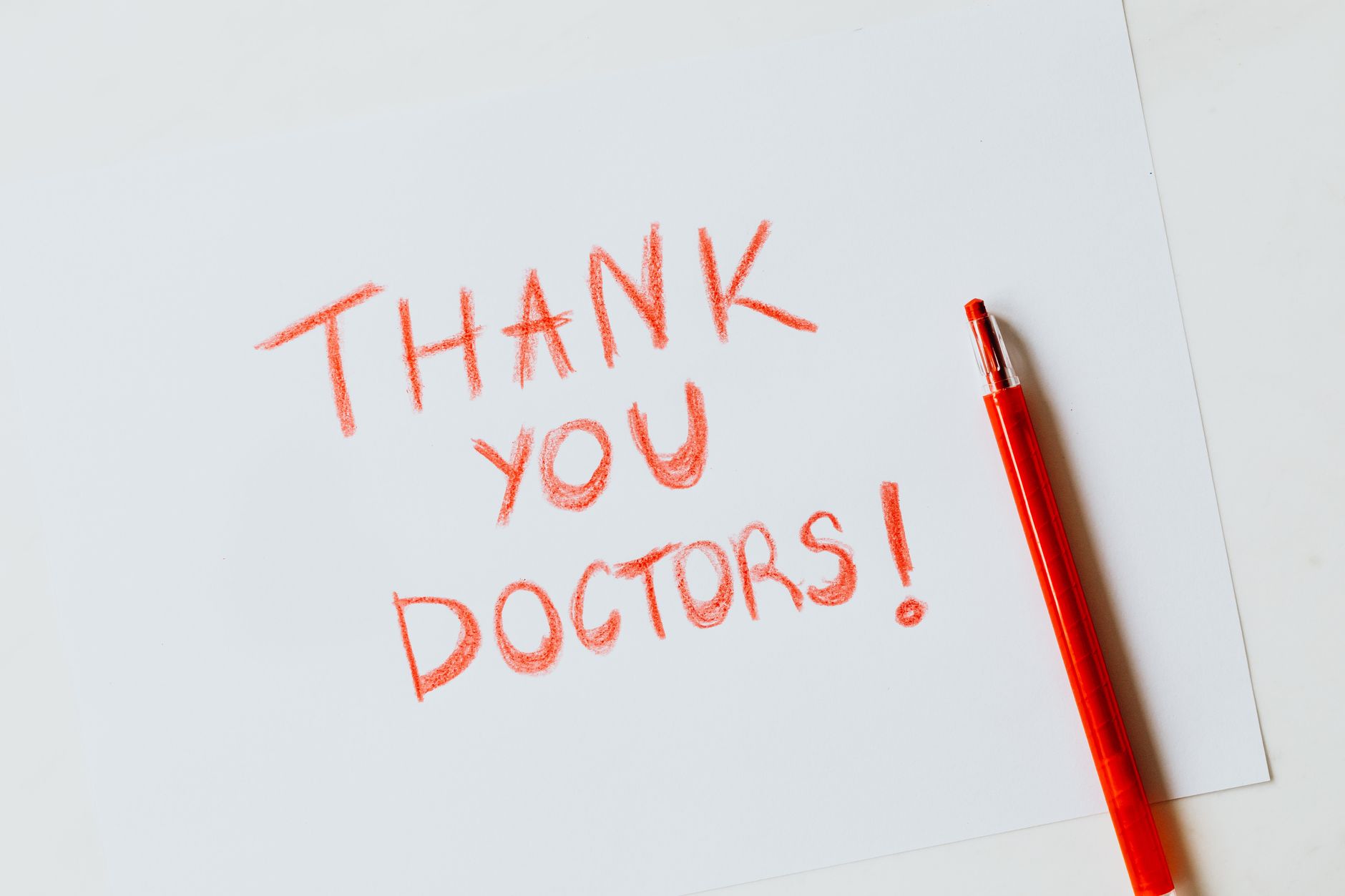christian thank you messages for support - A heartfelt handwritten 'Thank You Doctors' note in red on white paper with a matching red pencil.