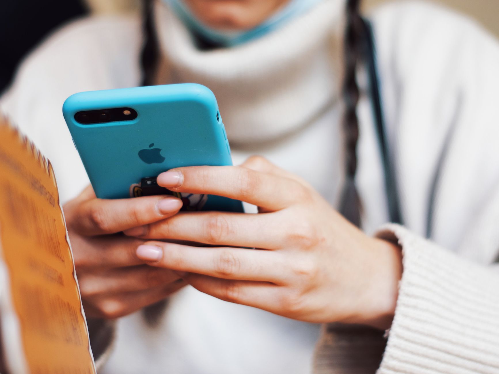 How to Adapt Messages for Different Customer Personalities - A person texting on a smartphone with a blue case indoors.