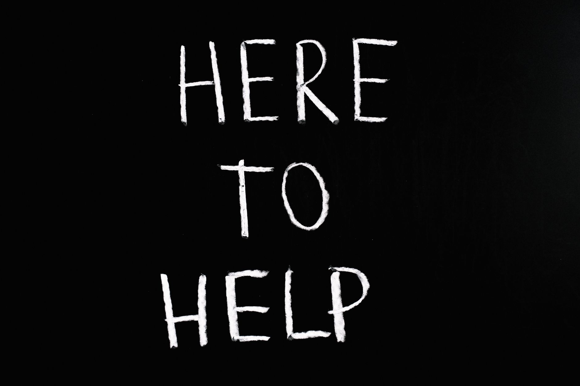 how to message support on outlier - White text 'Here to Help' on a minimalist black chalkboard background, conveying encouragement and support.