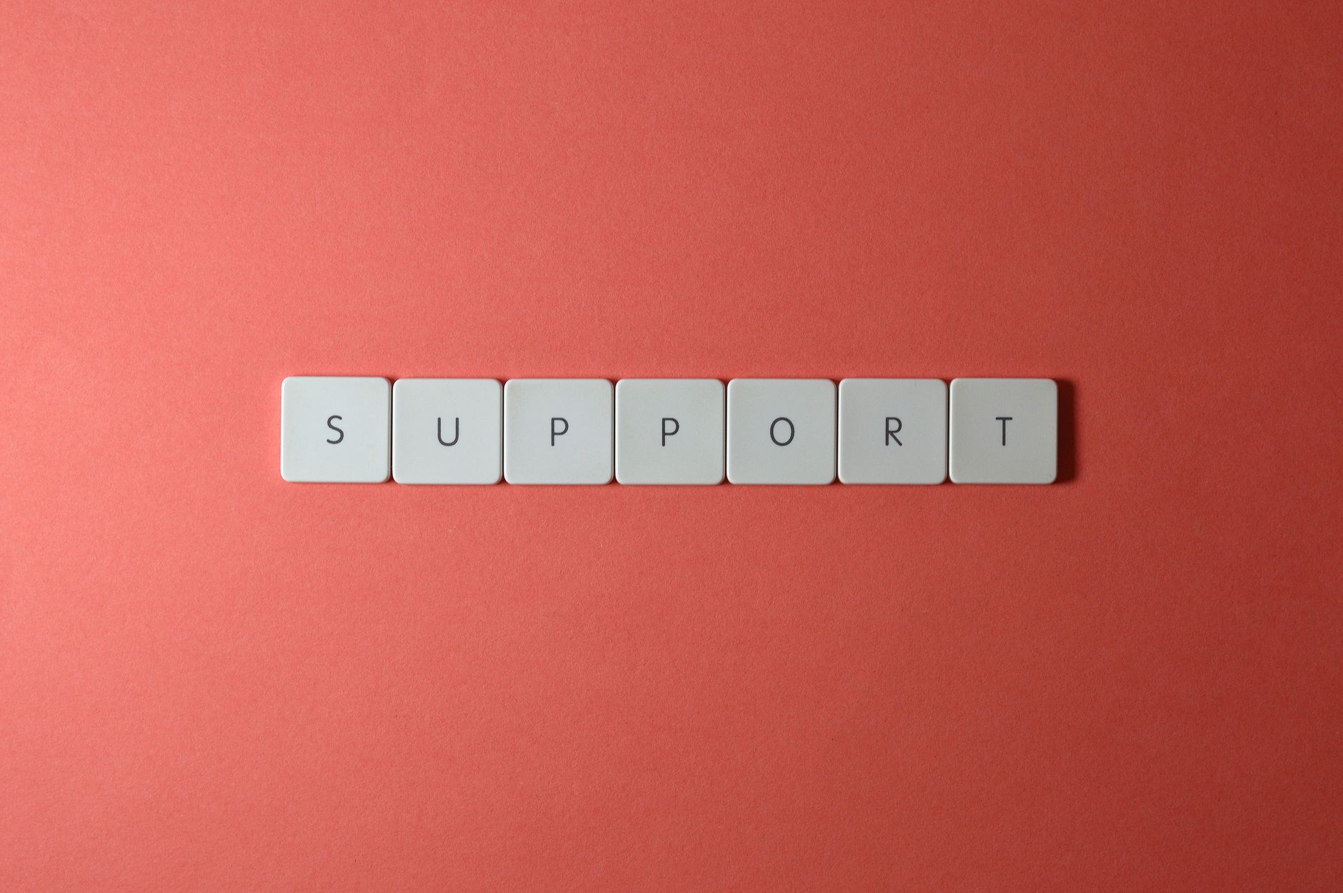 how to message support on outlier - Close-up of the word 'support' spelled with keyboard keys on a red background.