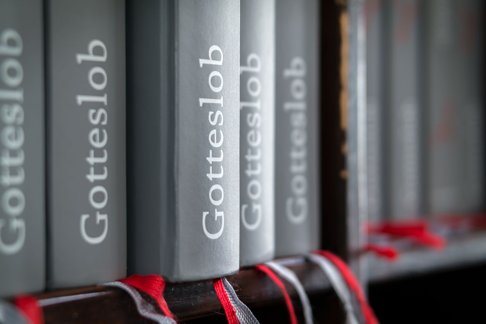 (no title) - Macro shot of Gotteslob hymn books with red bookmarks neatly arranged on a bookshelf.
