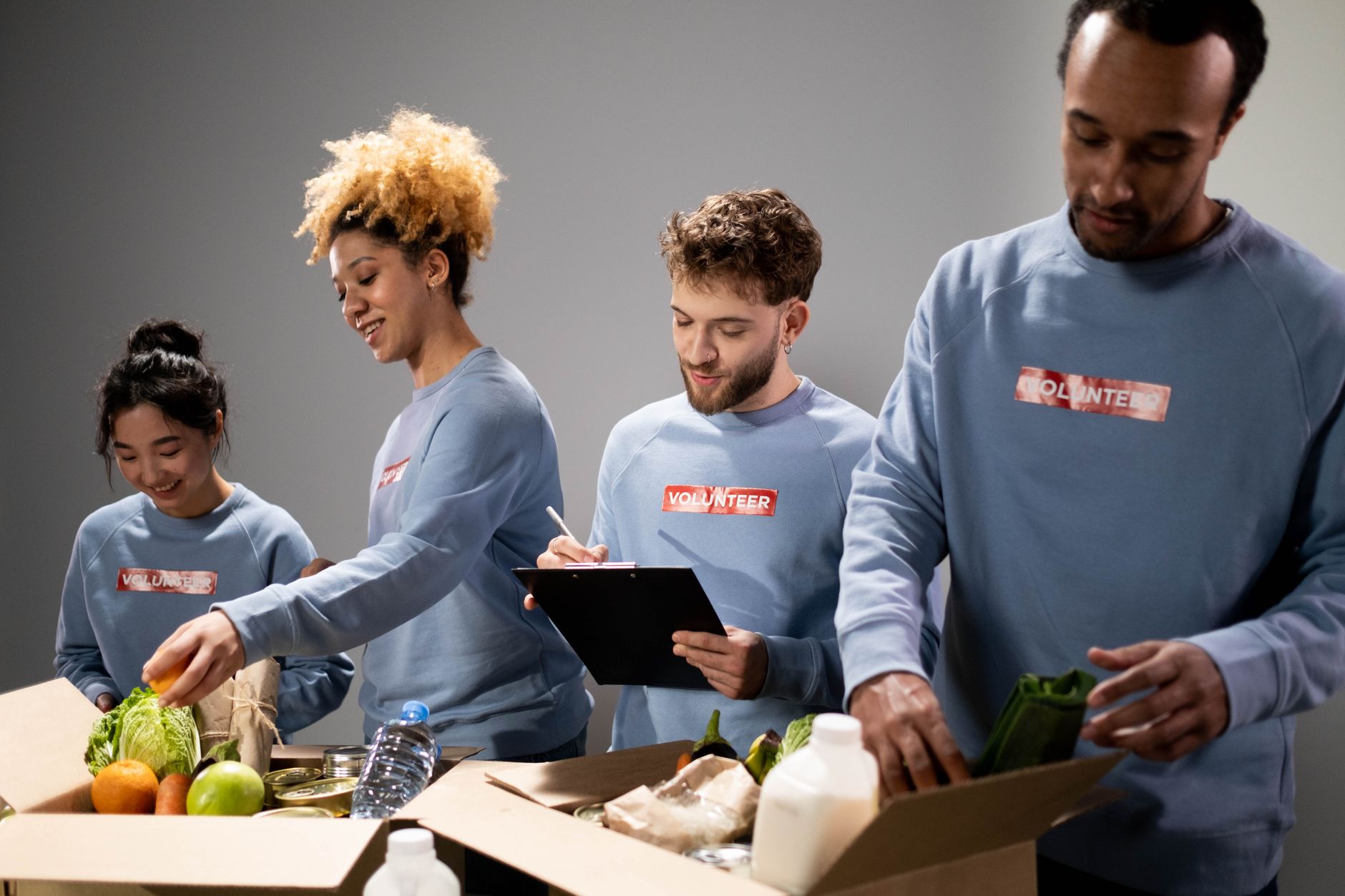 nonprofit organizations text messaging supporters engagement strategies - Four diverse volunteers pack food donations with teamwork and dedication.