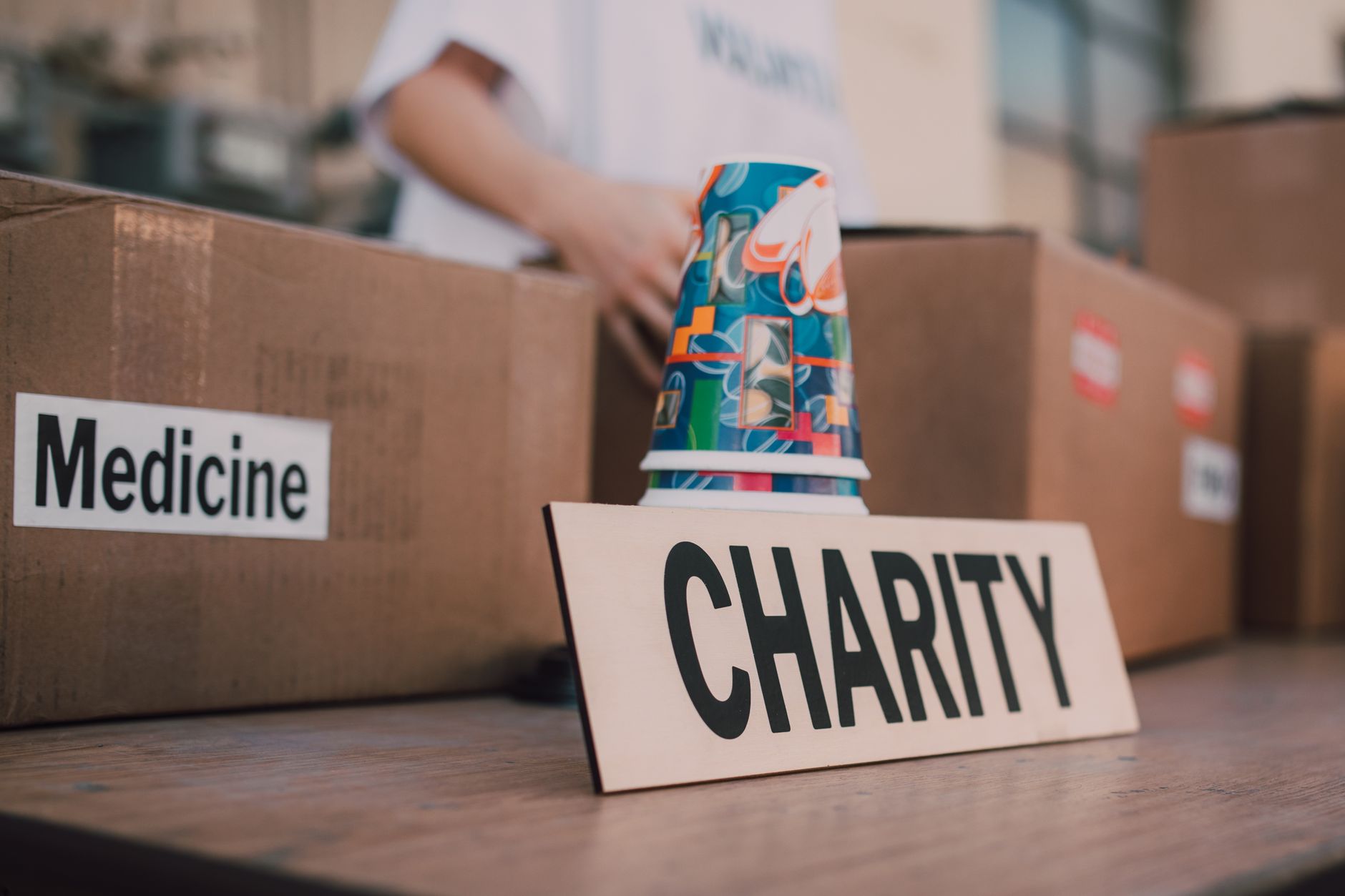 nonprofit organizations text messaging supporters fundraising - Close-up of charity boxes labeled for donation, featuring medicine and colorful paper cups.