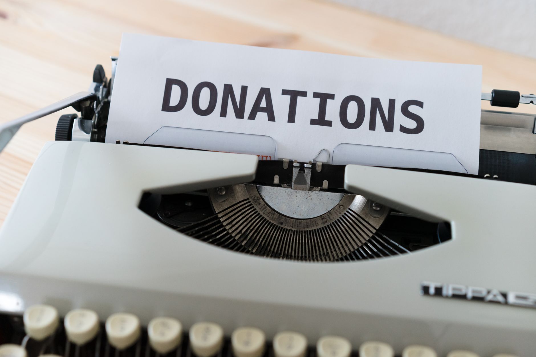 nonprofit organizations text messaging supporters fundraising - Close-up of a vintage typewriter with a paper displaying the word 'DONATIONS'.