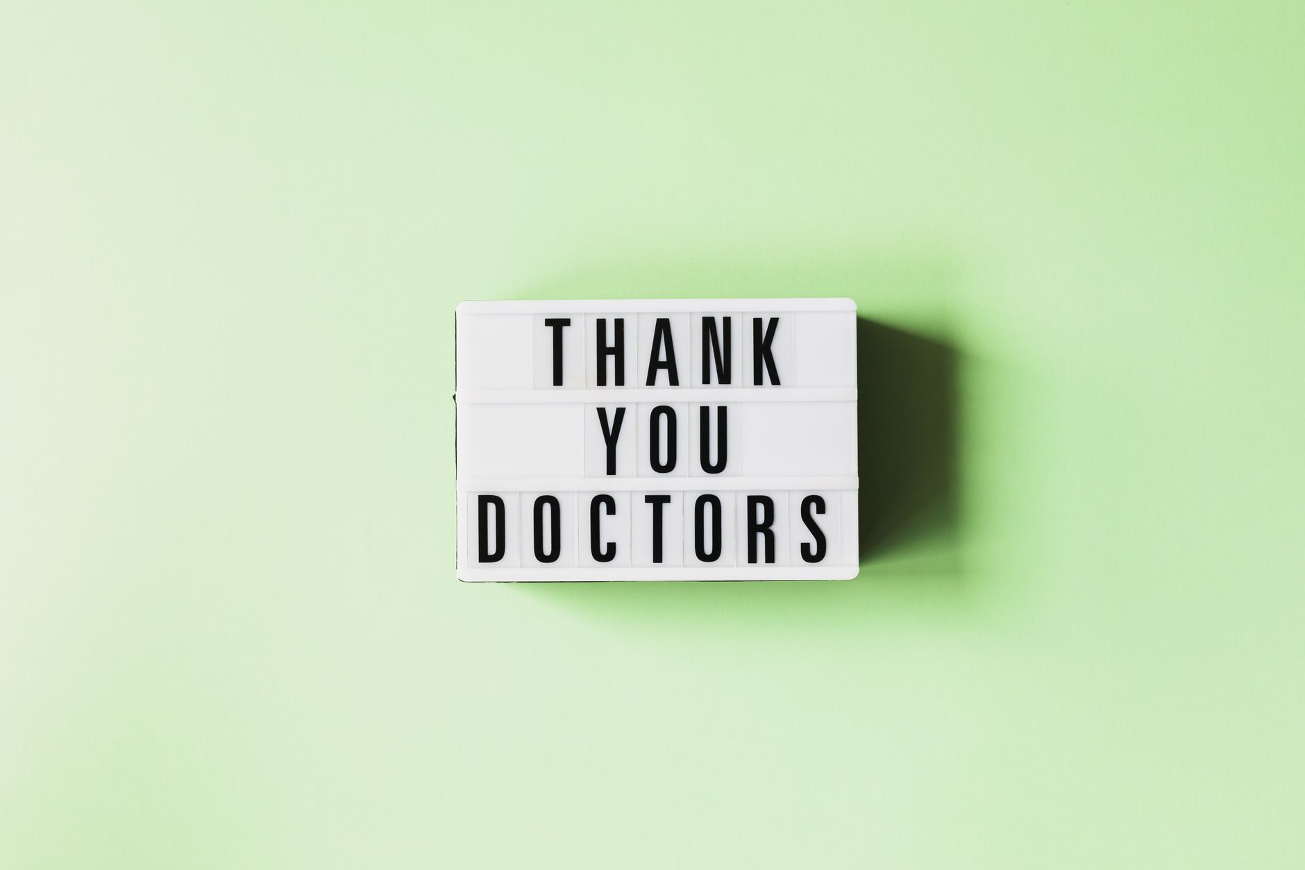 short thank you message for money support - Top view of retro light box with THANK YOU DOCTORS inscription placed on green surface