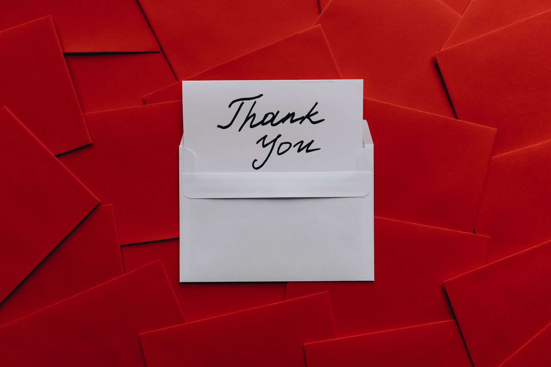 thank you message for colleague support - Elegant thank you card in white envelope on vibrant red envelopes flatlay. Perfect for gratitude themes.