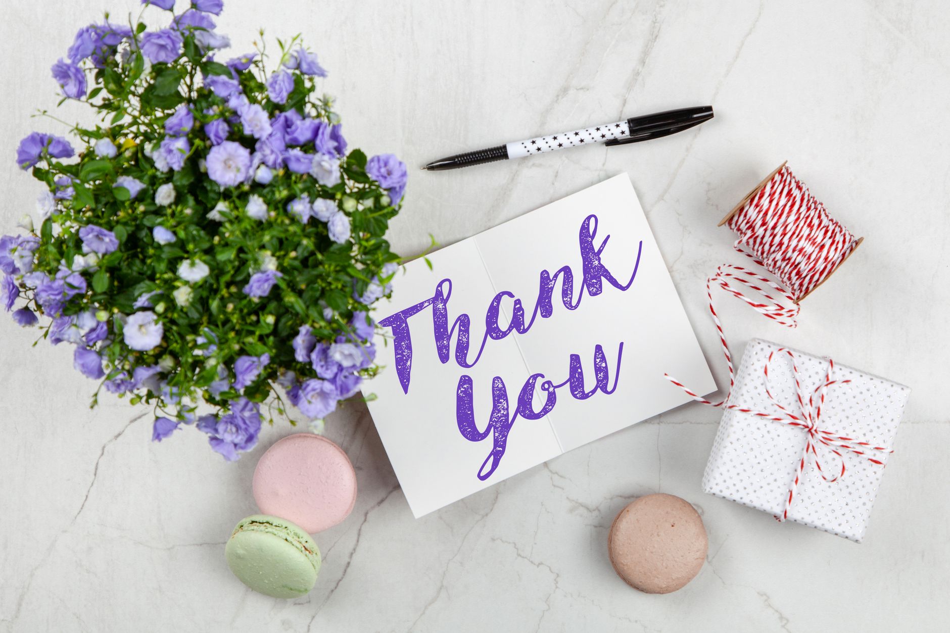 thank you message for colleague support - An elegant thank you card with flowers and a gift on a marble surface, perfect for expressing gratitude.