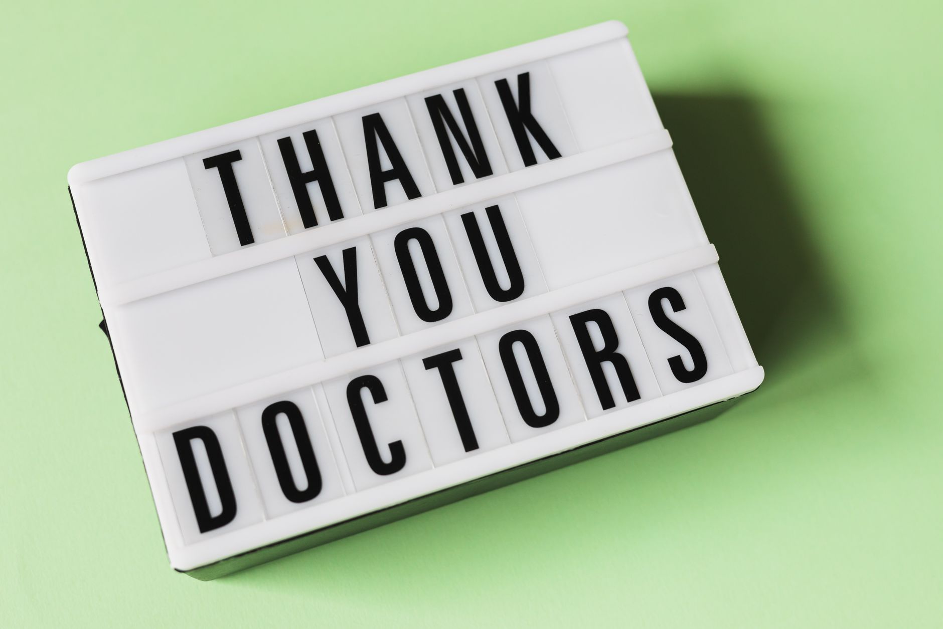 thank you message to church members for support - From above of vintage light box with THANK YOU DOCTORS gratitude message placed on green surface