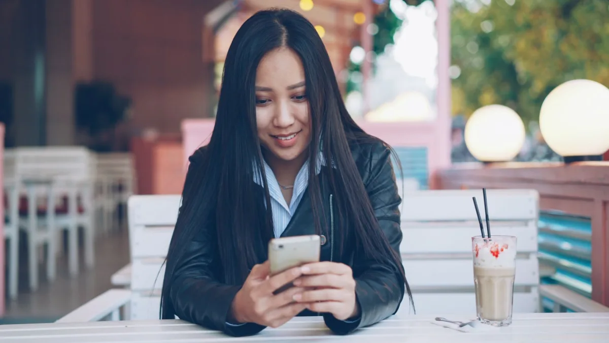 Young woman in a cafe using her phone, enjoying a coffee outdoors. Young woman in a cafe using her phone, enjoying a coffee outdoors.