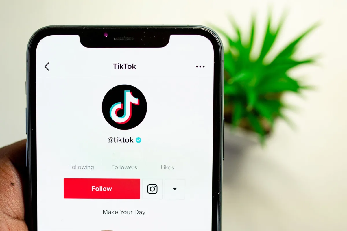 Close-up view of hand holding smartphone displaying TikTok app interface with profile page. Close-up view of hand holding smartphone displaying TikTok app interface with profile page.