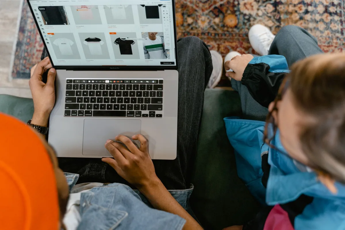 Two people browsing online clothing store on a laptop from above. Two people browsing online clothing store on a laptop from above.