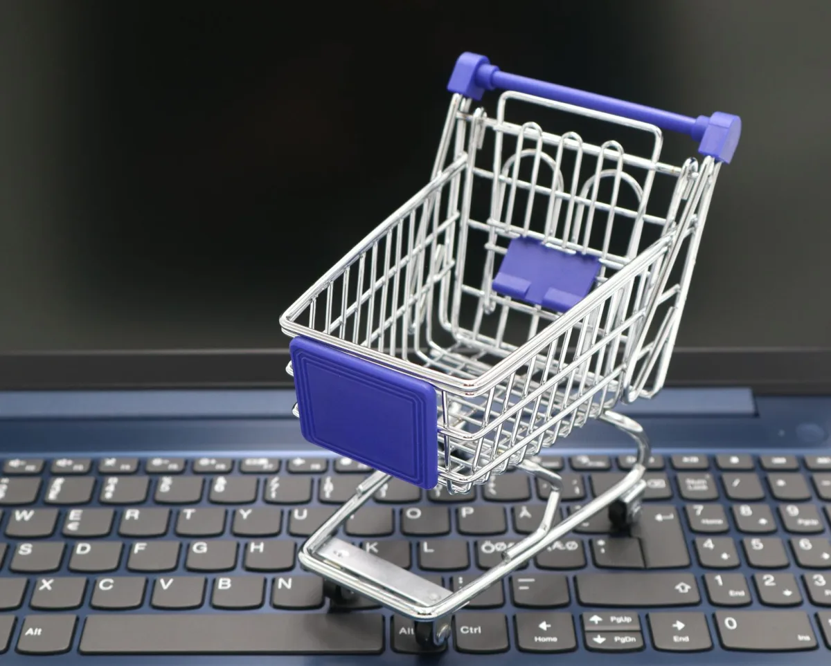A mini shopping cart placed on a laptop keyboard, symbolizing online shopping and digital retail. A mini shopping cart placed on a laptop keyboard, symbolizing online shopping and digital retail.