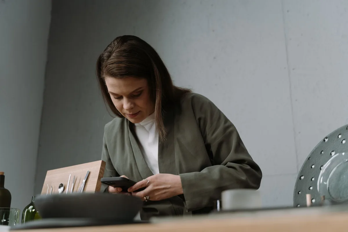 A woman focused on her smartphone while sitting at a stylish cafe table indoors. A woman focused on her smartphone while sitting at a stylish cafe table indoors.