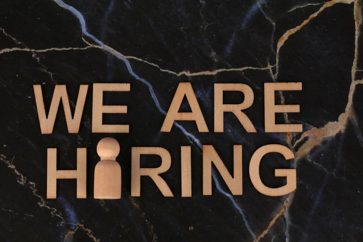 Wooden letters spell 'We Are Hiring' on dark marble surface. Wooden letters spell 'We Are Hiring' on dark marble surface.