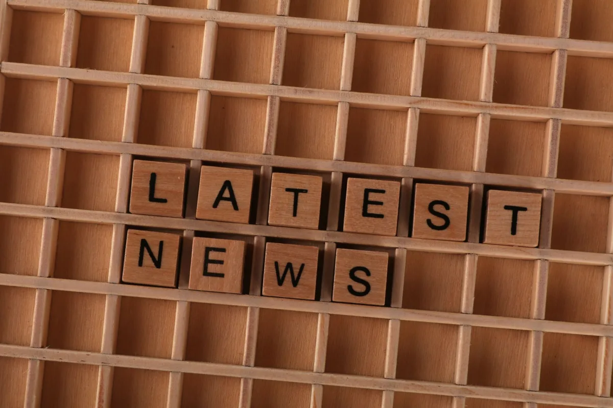 Wooden letter blocks spelling Latest News on a grid background, ideal media themes.