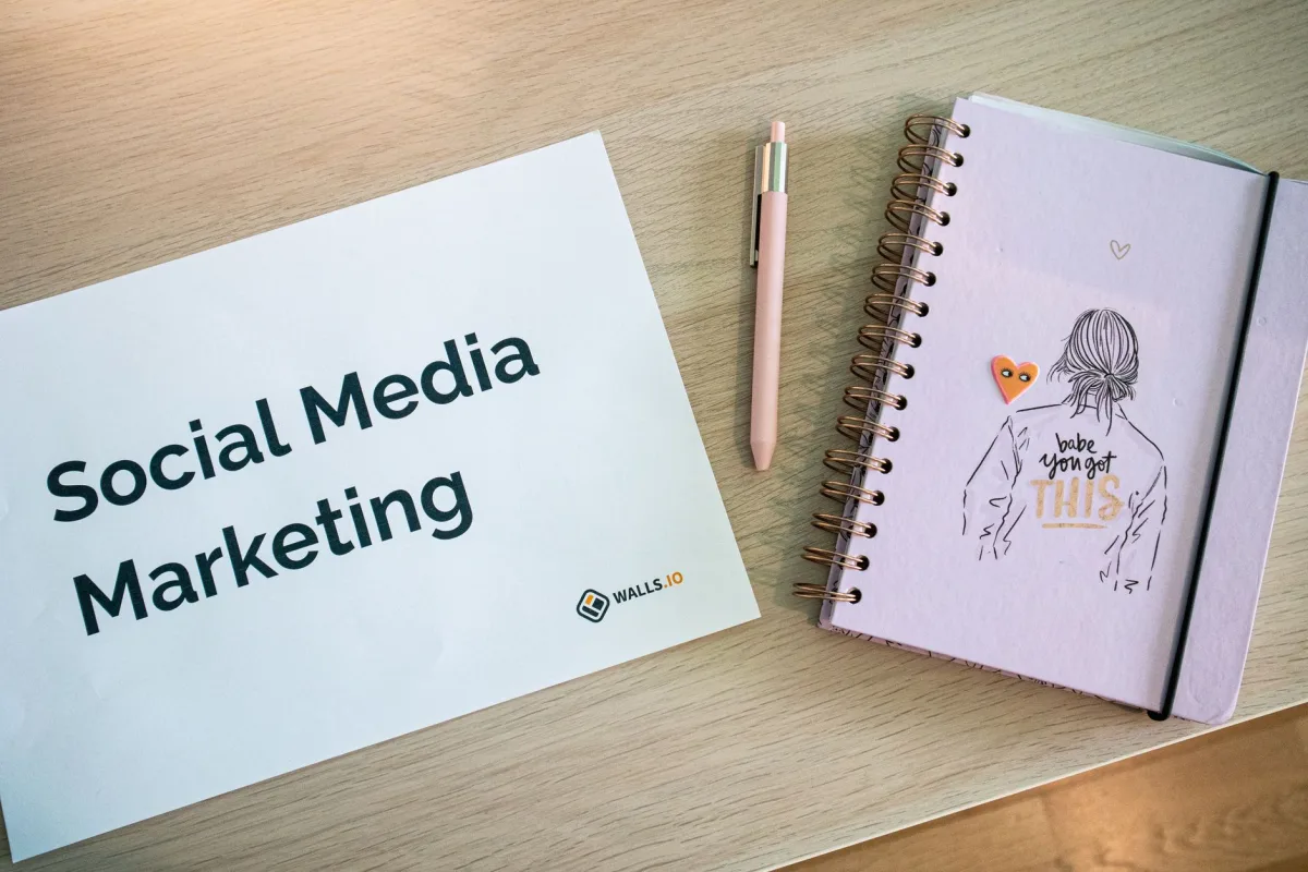 Flat lay of marketing paper and motivational notebook on wooden desk.