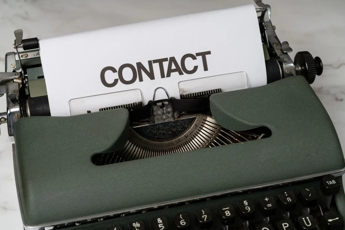 Classic green typewriter with 'CONTACT' typed on paper, retro style.