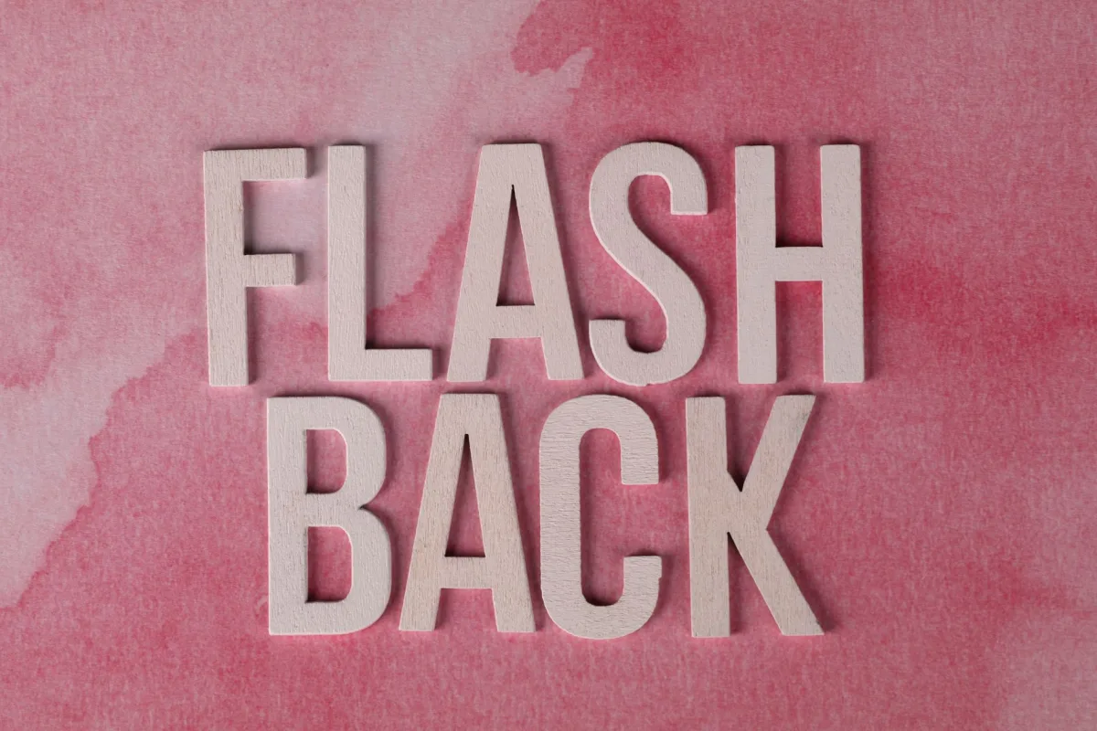 The word 'Flashback' in wooden letters on a pink watercolor background, creating a nostalgic theme.