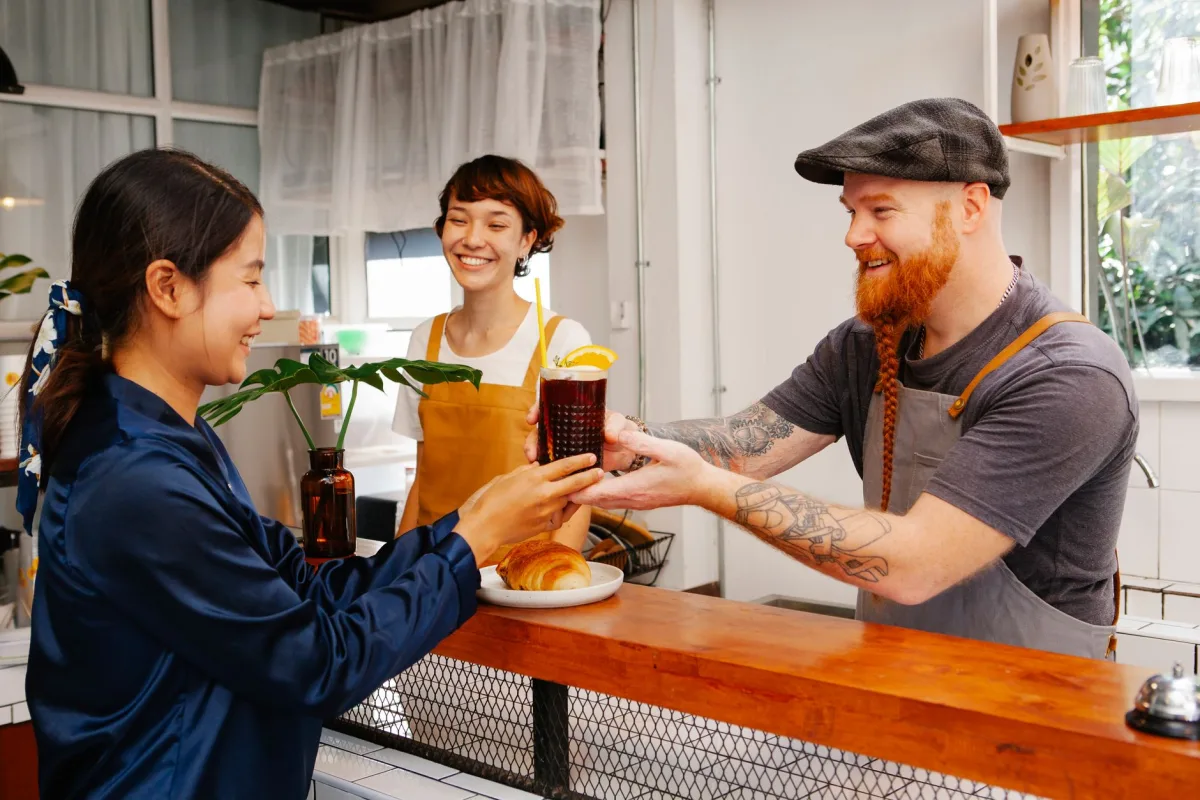 Glad hipster male employee passing glass of Black Velvet cocktail to smiling ethnic colleague at work Glad hipster male employee passing glass of Black Velvet cocktail to smiling ethnic colleague at work