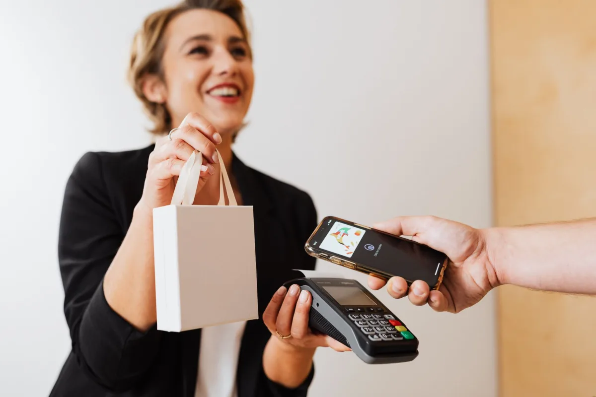 Smiling cashier handles a purchase with a contactless mobile payment in a modern shop. Smiling cashier handles a purchase with a contactless mobile payment in a modern shop.