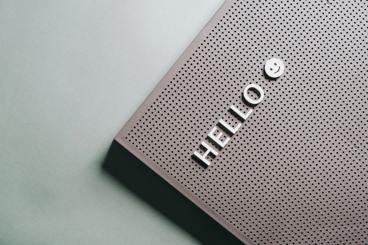 A close-up of a perforated board displaying the text 'HELLO' and a smiley face in a minimalist design.
