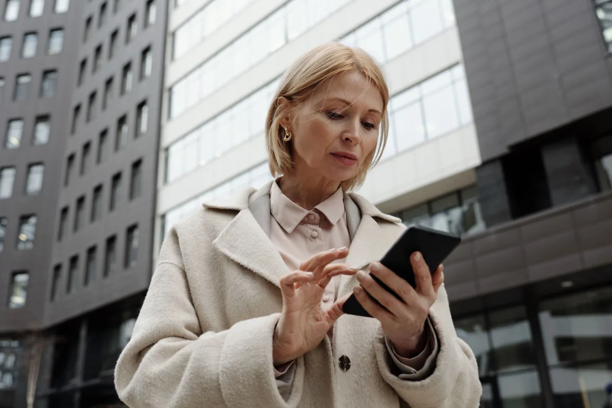Woman in coat using smartphone in front of modern Professional and focused expression. Woman in coat using smartphone in front of modern Professional and focused expression.