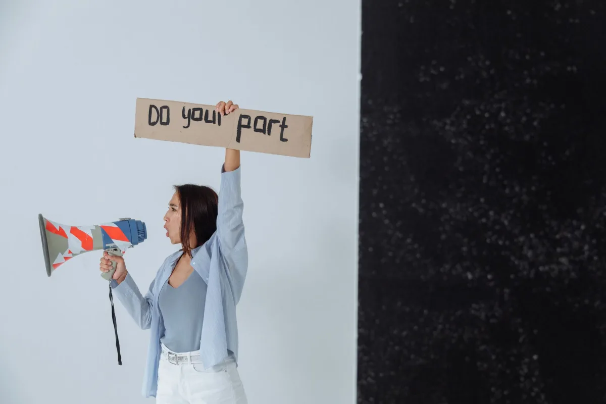 Woman holding a sign and megaphone in a studio setting, encouraging action. Woman holding a sign and megaphone in a studio setting, encouraging action.