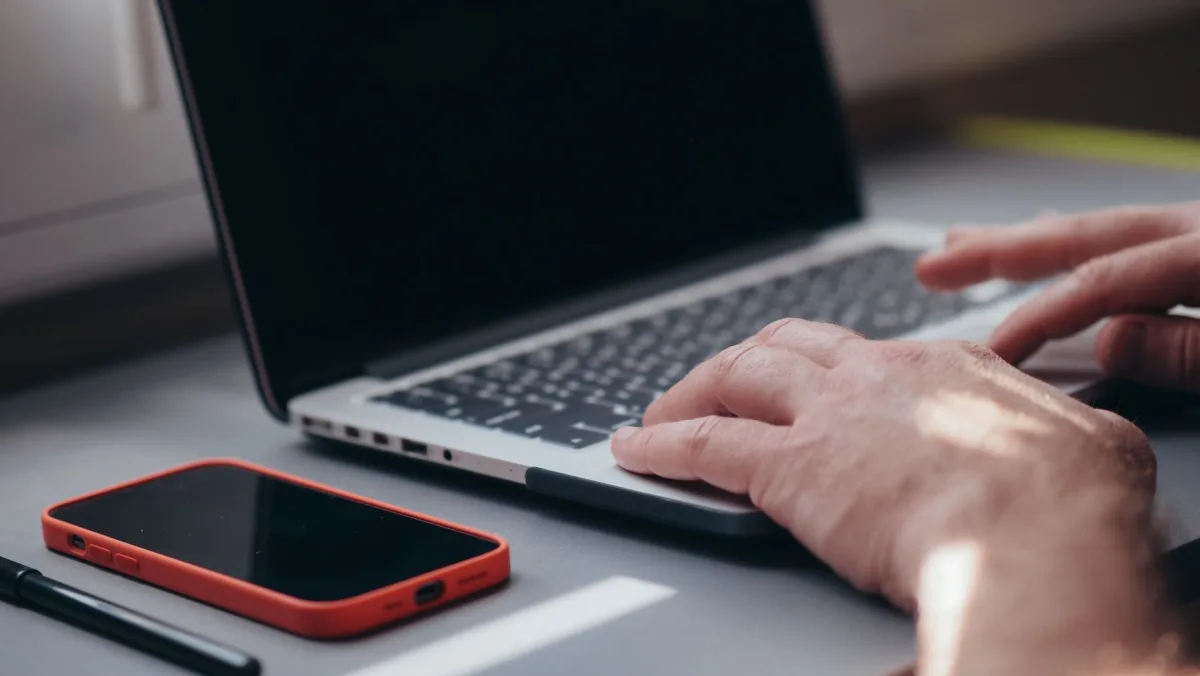 Close-up of hands typing on a laptop beside a smartphone. Ideal for tech and work themes. Close-up of hands typing on a laptop beside a smartphone. Ideal for tech and work themes.