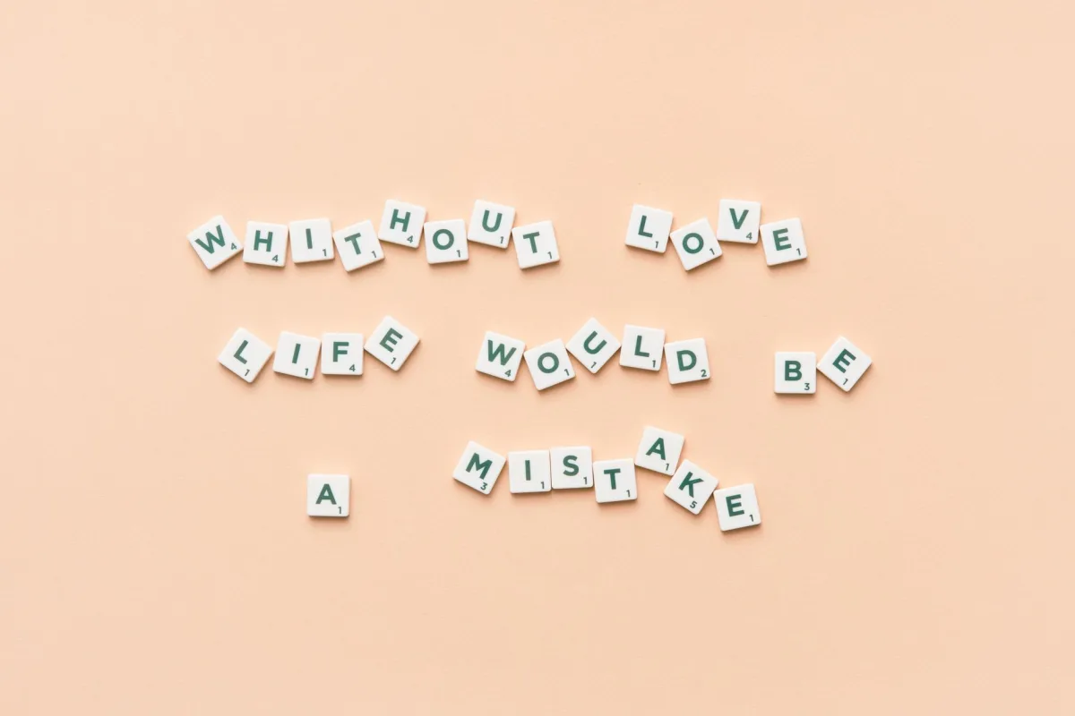 Scrabble tiles forming the phrase 'Without love life would be a mistake' on a beige background.