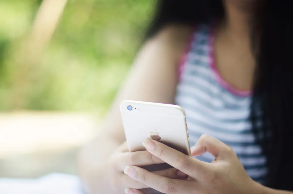 A woman using a smartphone outdoors in a relaxed setting. A woman using a smartphone outdoors in a relaxed setting.