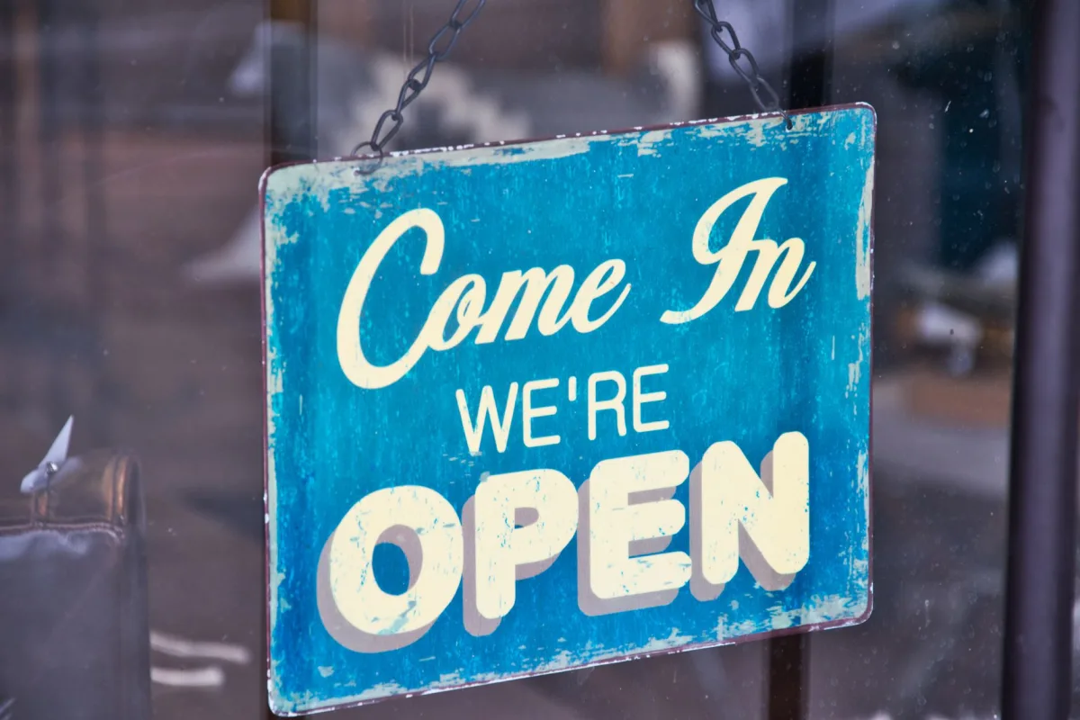 Retro blue open sign on a shop glass door inviting customers in. Retro blue open sign on a shop glass door inviting customers in.