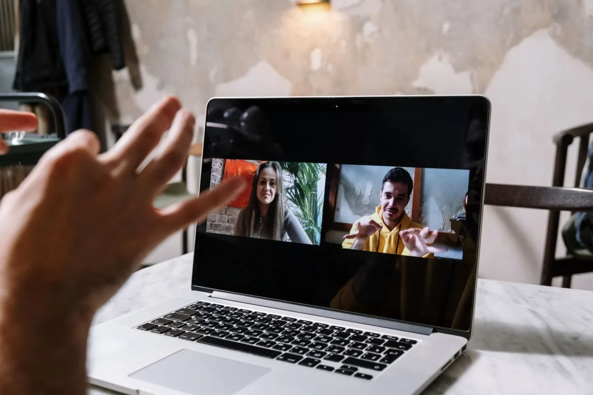 Hands gesturing during a video call on a laptop screen, showing two people in a virtual meeting. Hands gesturing during a video call on a laptop screen, showing two people in a virtual meeting.