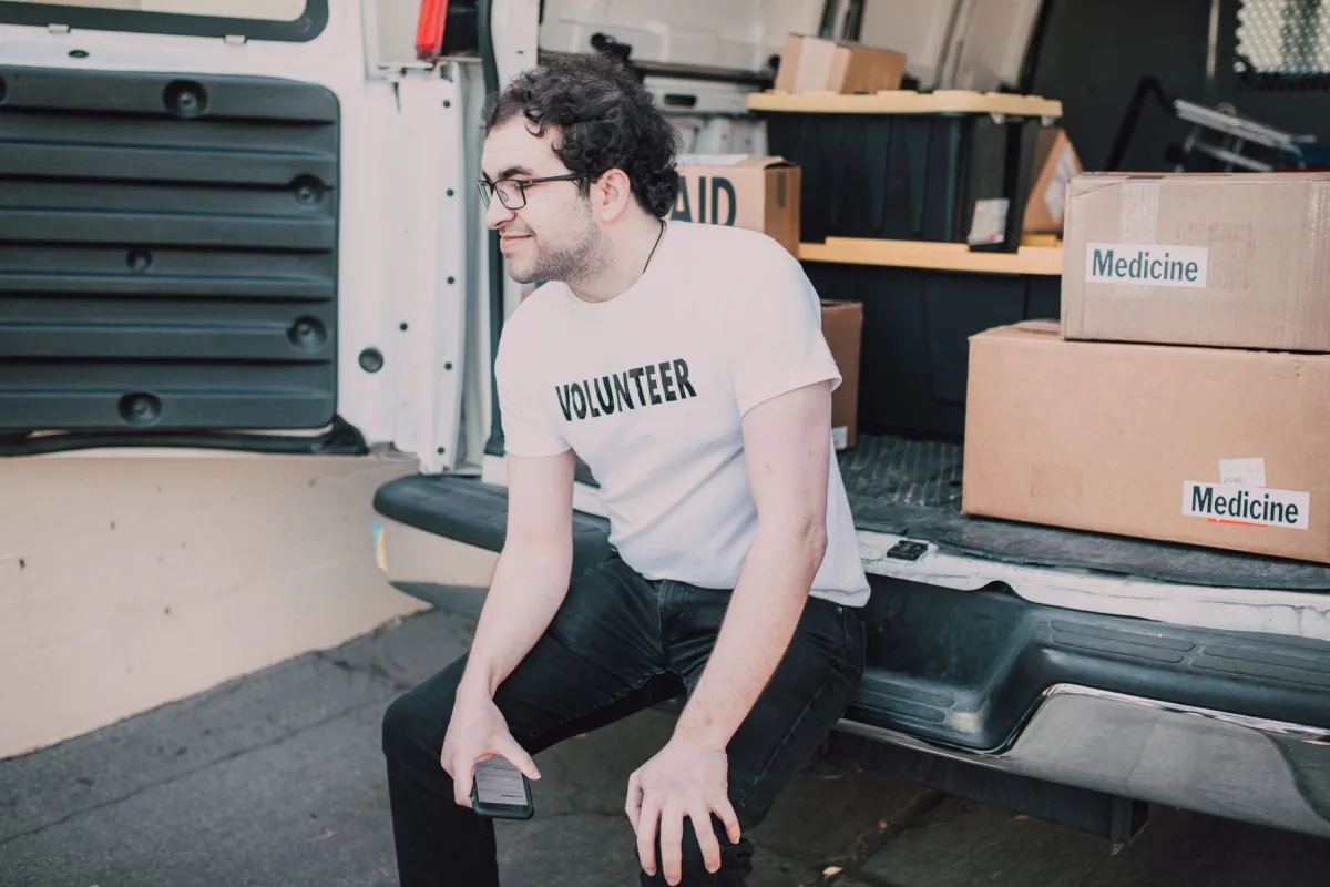 A volunteer sitting in a van organizing medicine boxes for shipment.