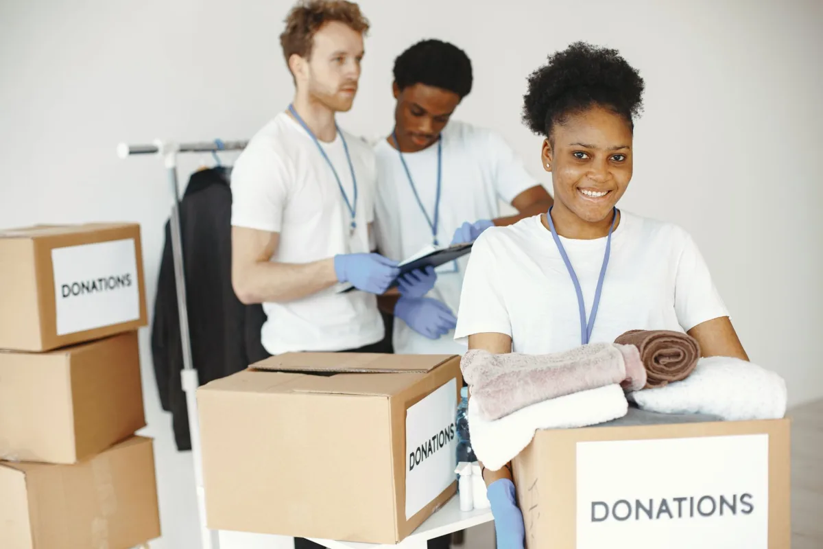 Group of volunteers smiling while sorting donation boxes indoors for a charity organization. Group of volunteers smiling while sorting donation boxes indoors for a charity organization.