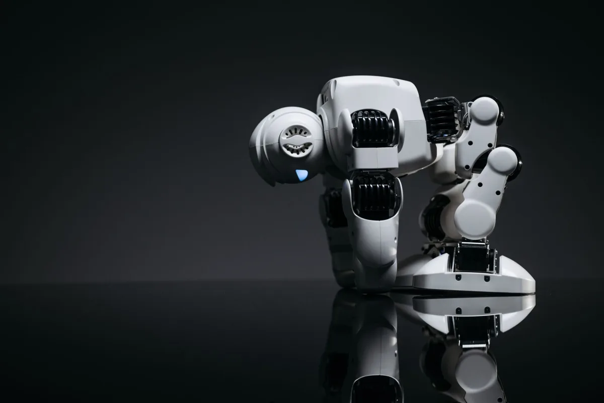 A modern robot toy depicted in a studio environment with its reflection visible on a dark surface. A modern robot toy depicted in a studio environment with its reflection visible on a dark surface.