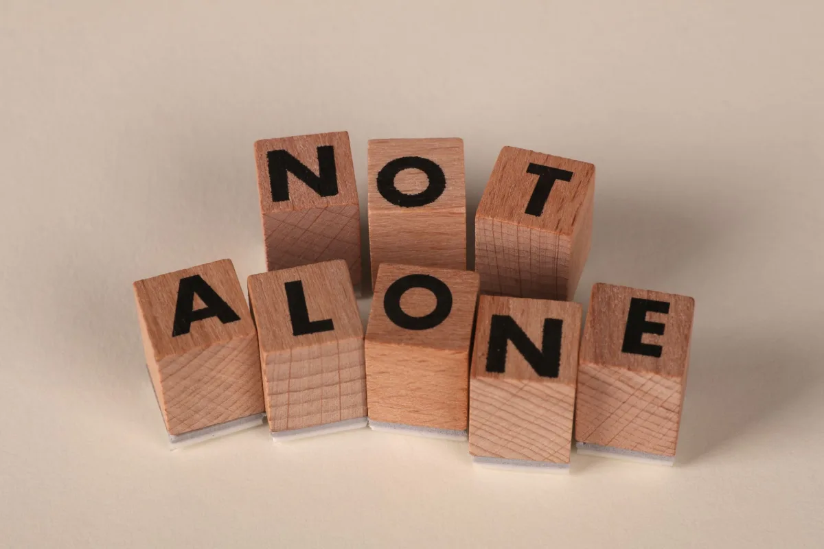 Wooden blocks arranged to spell 'Not Alone', symbolizing and community. Wooden blocks arranged to spell 'Not Alone', symbolizing and community.