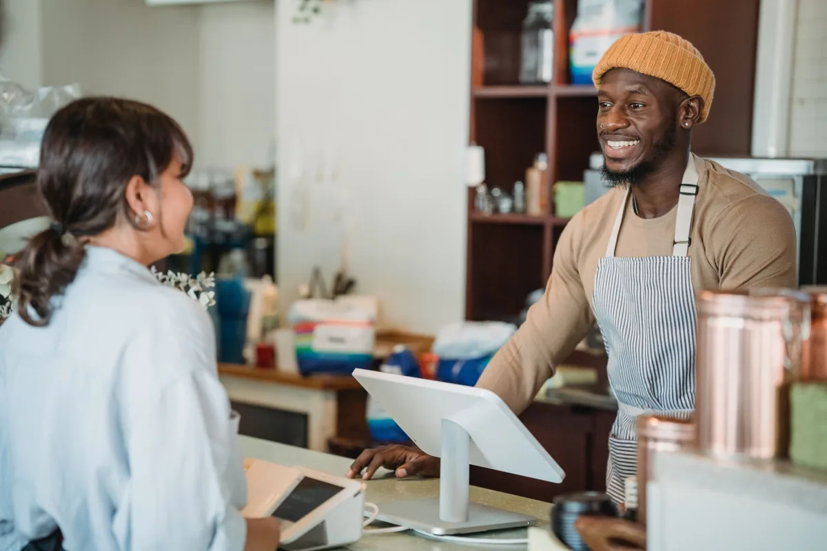 A cheerful barista engaging with a at a café counter, a welcoming atmosphere. A cheerful barista engaging with a at a café counter, a welcoming atmosphere.
