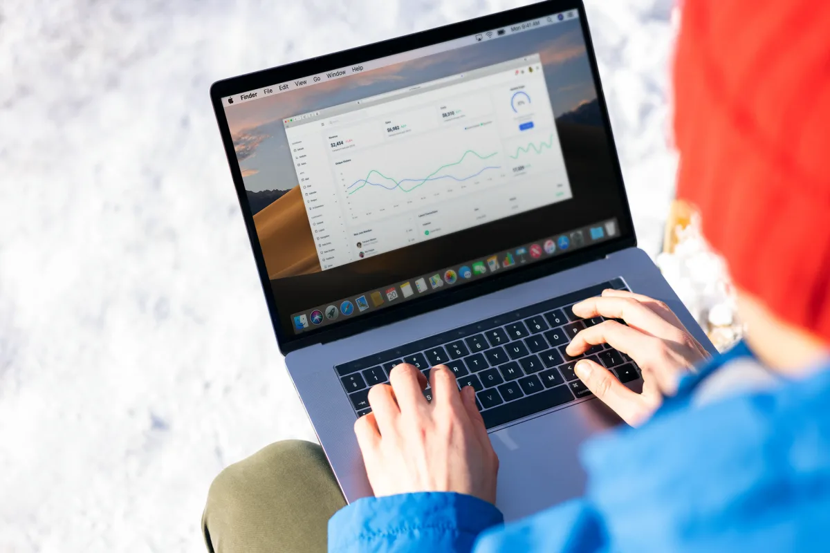 A person in a blue jacket analyzing business on a laptop outdoors during winter.