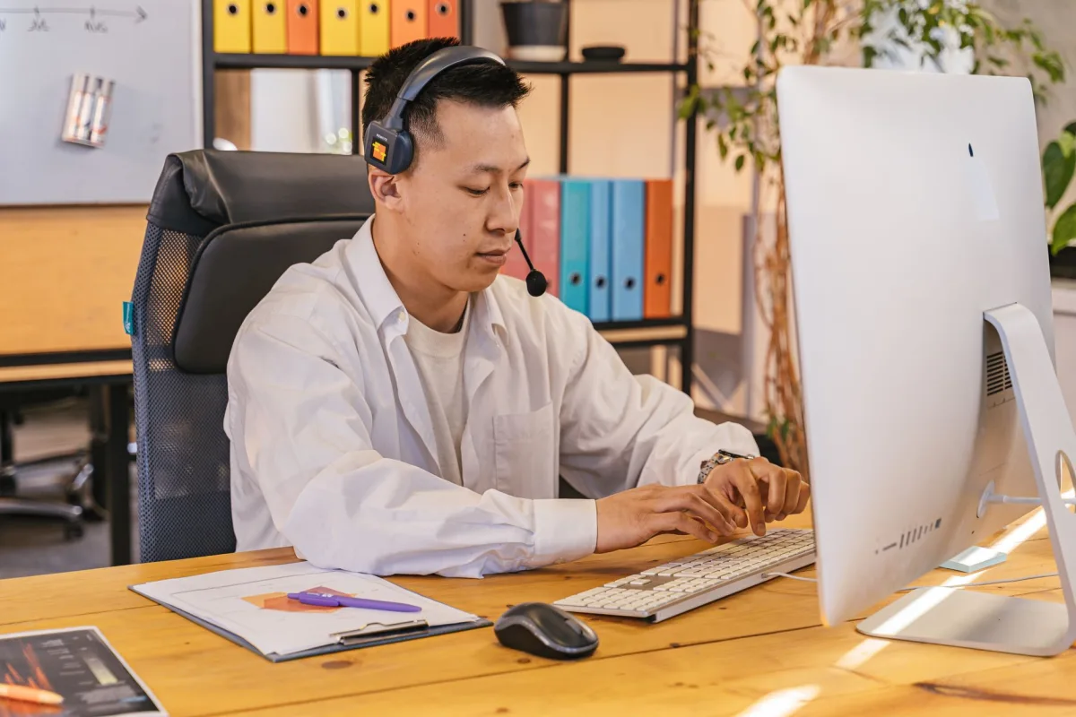 Businessman working on computer at office desk with headset, focusing on tasks. Businessman working on computer at office desk with headset, focusing on tasks.