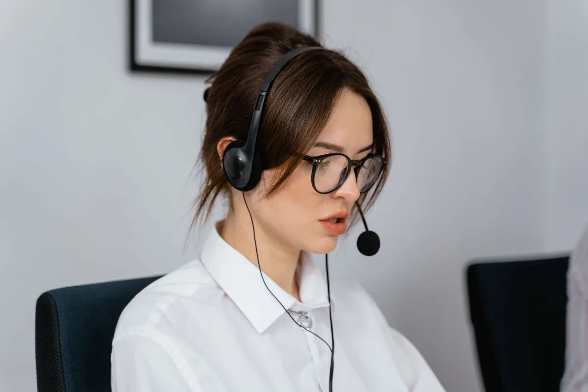 Focused woman working in a call center with a headset, providing customer communication services.