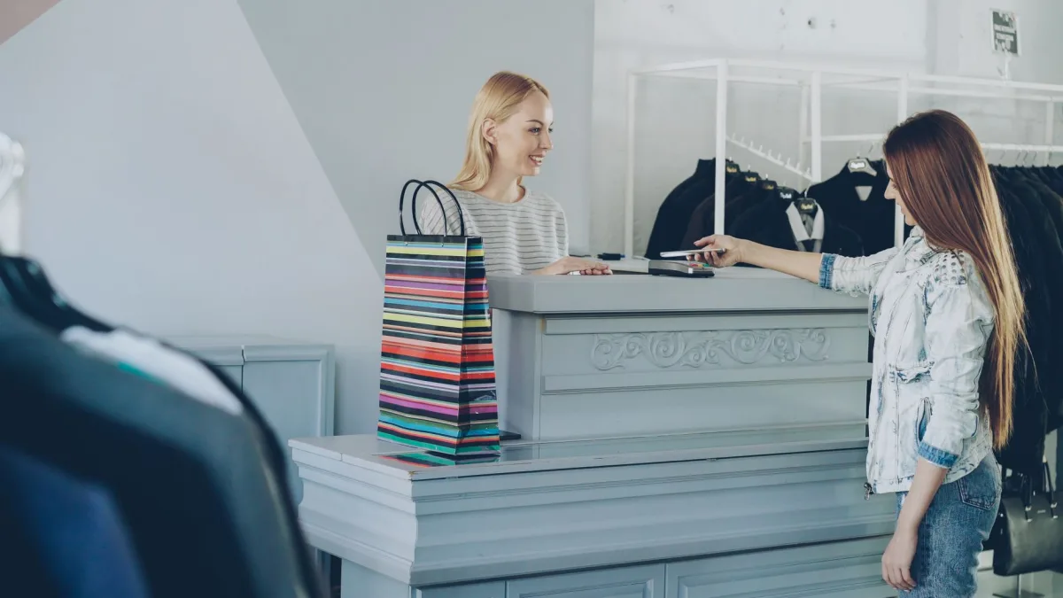 interacting with cashier at boutique counter with shopping bags.