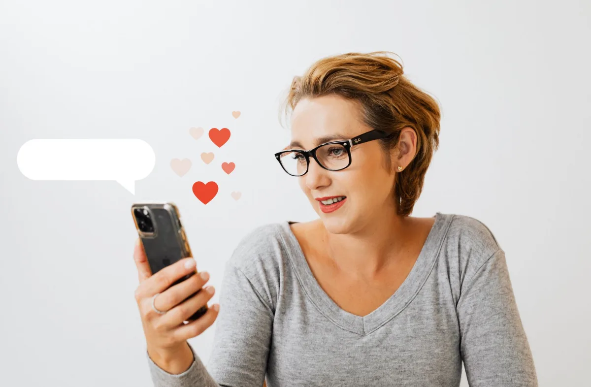 Adult woman wearing eyeglasses and using phone, surrounded by digital love heart symbols on a white background. Adult woman wearing eyeglasses and using phone, surrounded by digital love heart symbols on a white background.