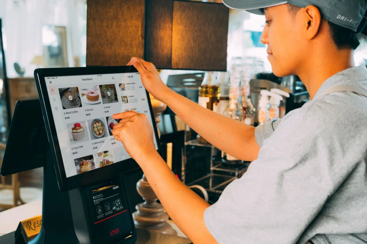 A cafe worker navigating a modern touchscreen system to manage orders efficiently. A cafe worker navigating a modern touchscreen system to manage orders efficiently.