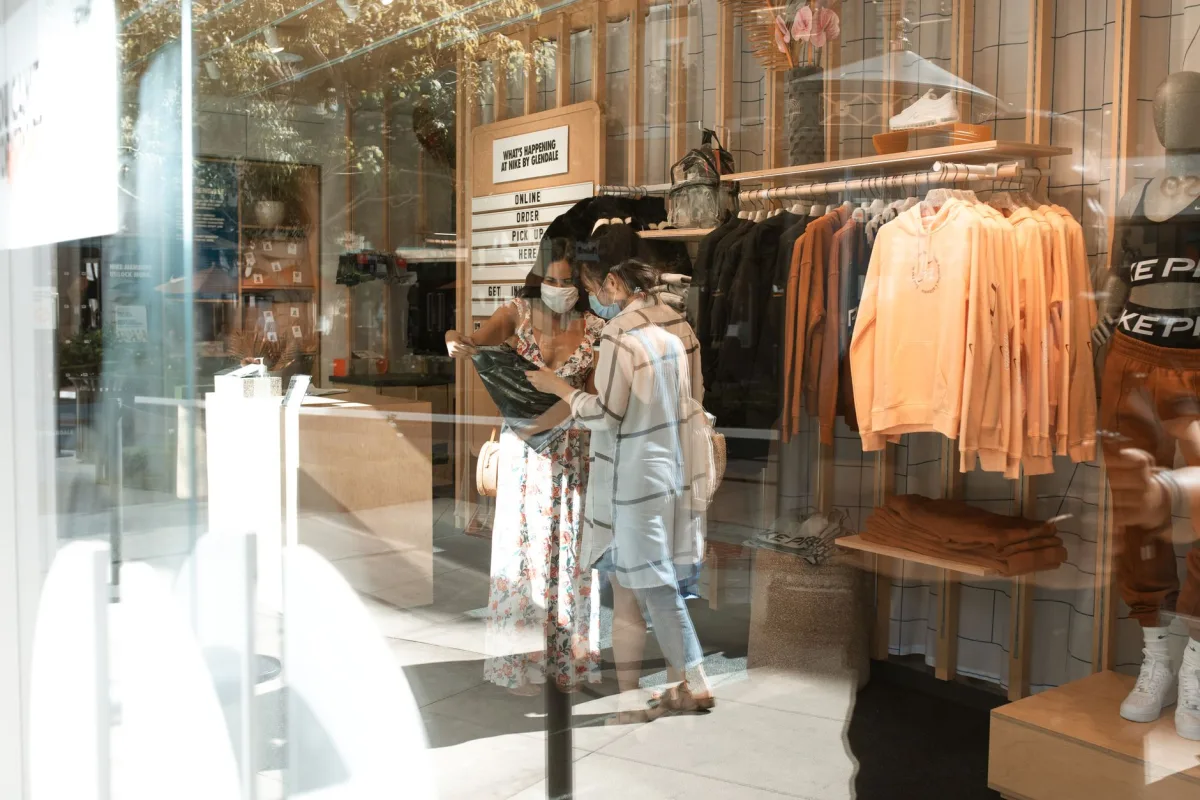 Two women wearing face masks shop in a trendy boutique amid pandemic precautions. Two women wearing face masks shop in a trendy boutique amid pandemic precautions.