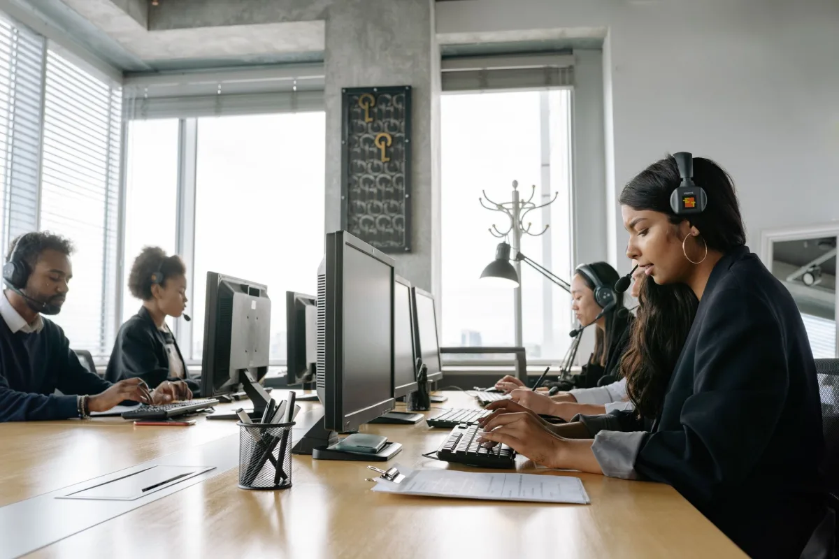 A team of call center agents working in a modern office with headsets and computers. A team of call center agents working in a modern office with headsets and computers.