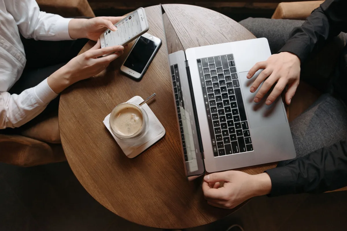 Overhead view of professionals using technology devices at a café table.
