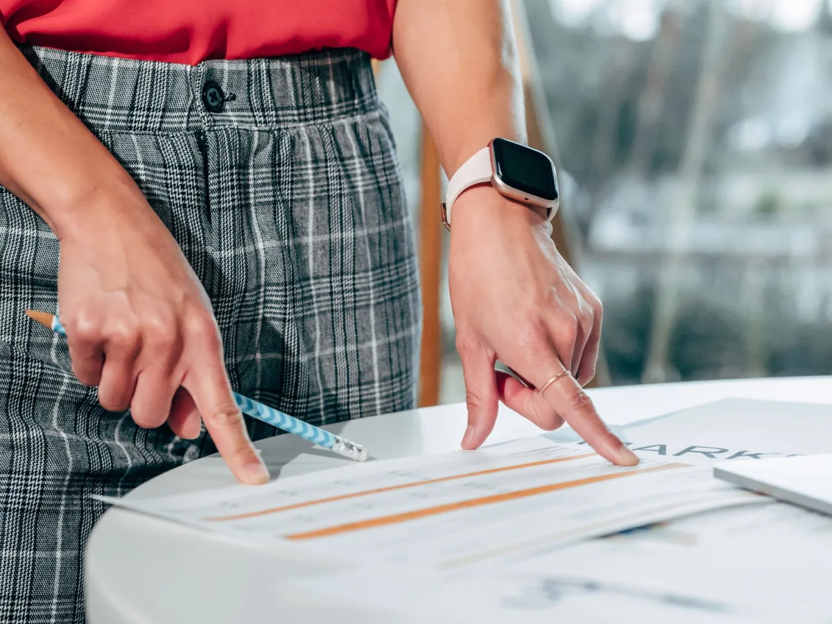 Businesswoman examining documents on a desk with a smartwatch and pen. Businesswoman examining documents on a desk with a smartwatch and pen.
