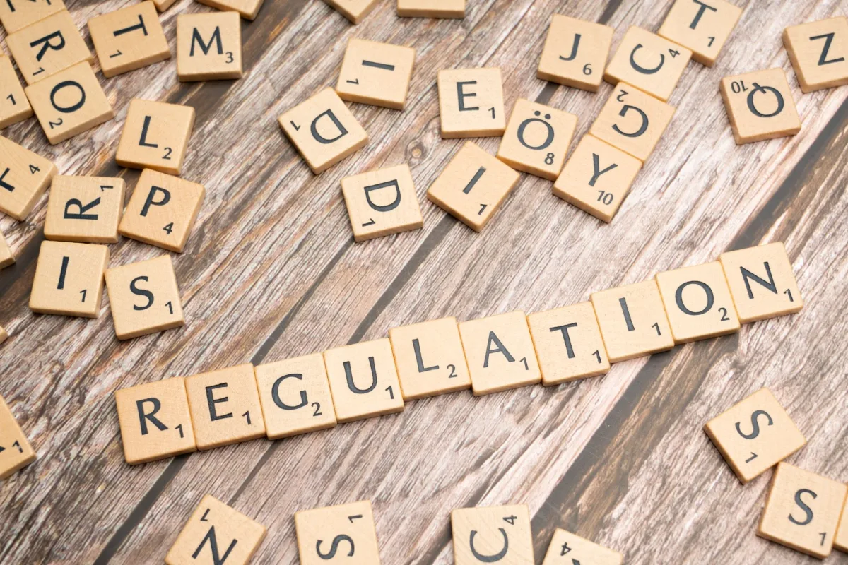 Wooden letter tiles spelling 'Regulation' on a textured wood background, conveying themes of compliance and structure. Wooden letter tiles spelling 'Regulation' on a textured wood background, conveying themes of compliance and structure.