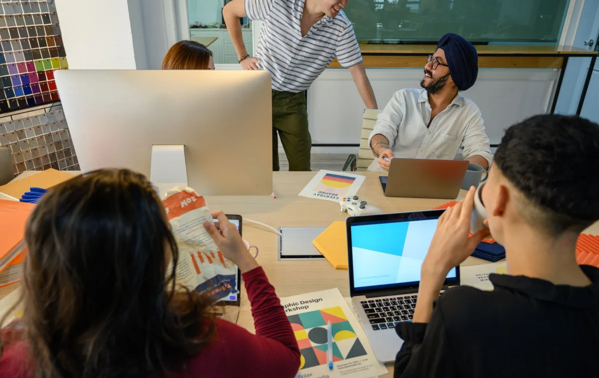 A group of diverse professionals collaborate on a design project in a modern office setting.